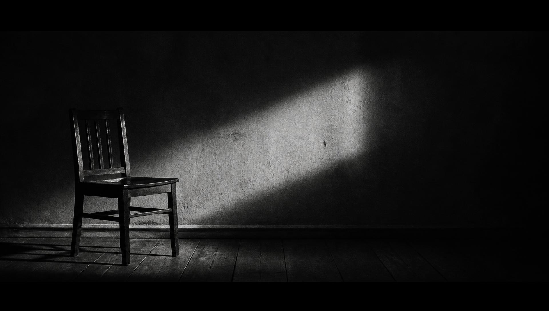A single chair in an empty room, lit by one shaft of light